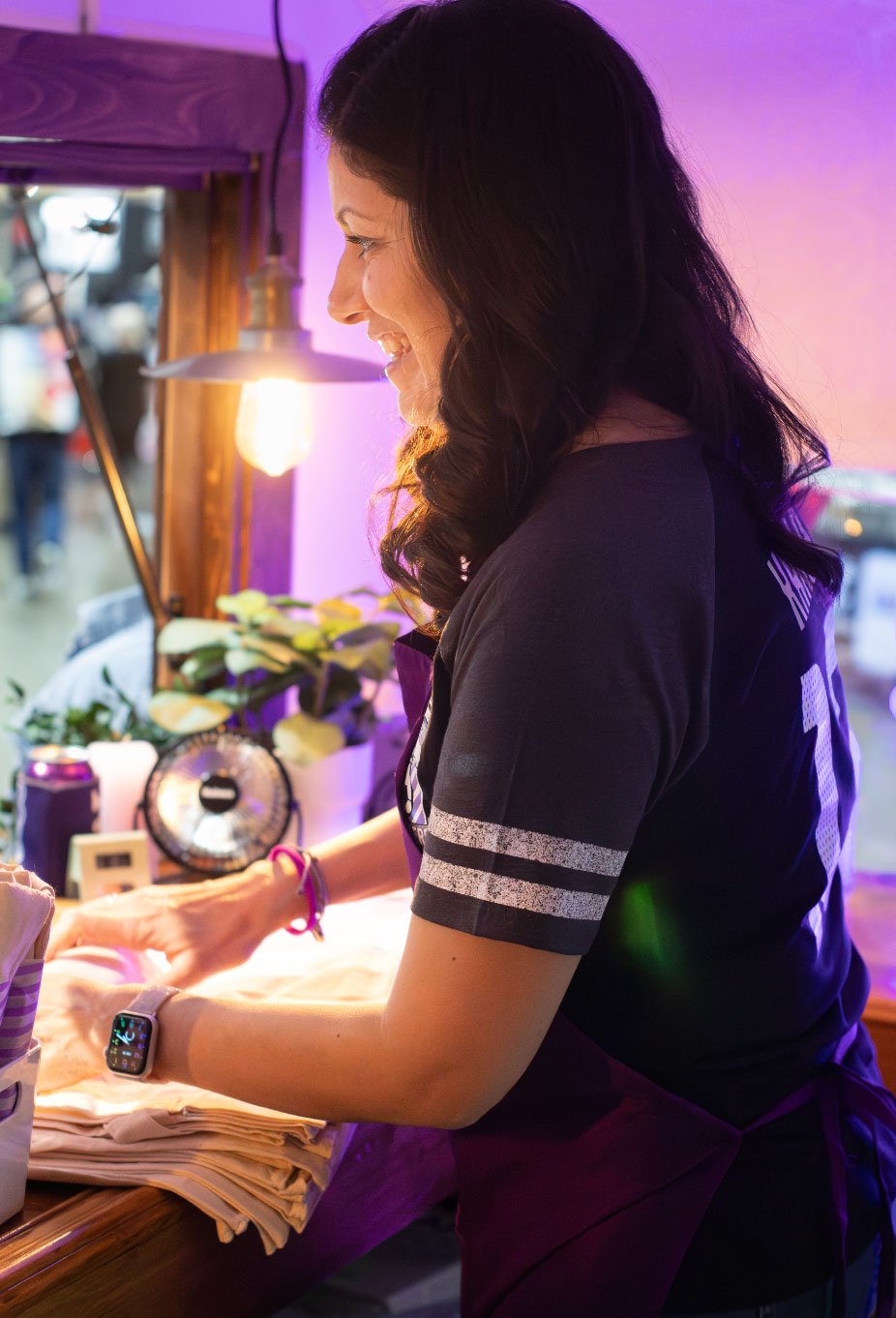 A woman in a food truck smiling as she looks out the main window.